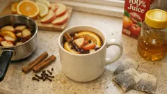 Šálek horkého jablečného moštu se skořicí, hřebíčkem a plátky jablek