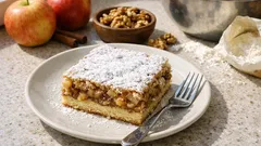 Jablečný koláč s ořechy a moučkovým cukrem na talíři