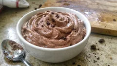 Čokoládový mousse v bílé misce s lžičkou na stole