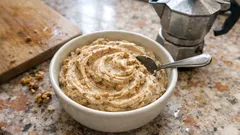 Miska hummusu se lžící na kuchyňské desce