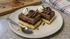 Čokoládové řezy s krémem a šlehačkou na talíři s lžičkou