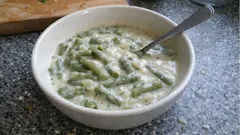 Miska se smetanovou okurkovou omáčkou s koprem a lžící na stole